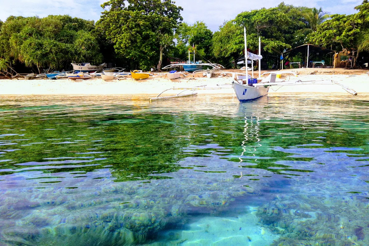 Outrigger boats off the white-sand shore of Balicasag Island Marine Sanctuary in Bohol, Philippines