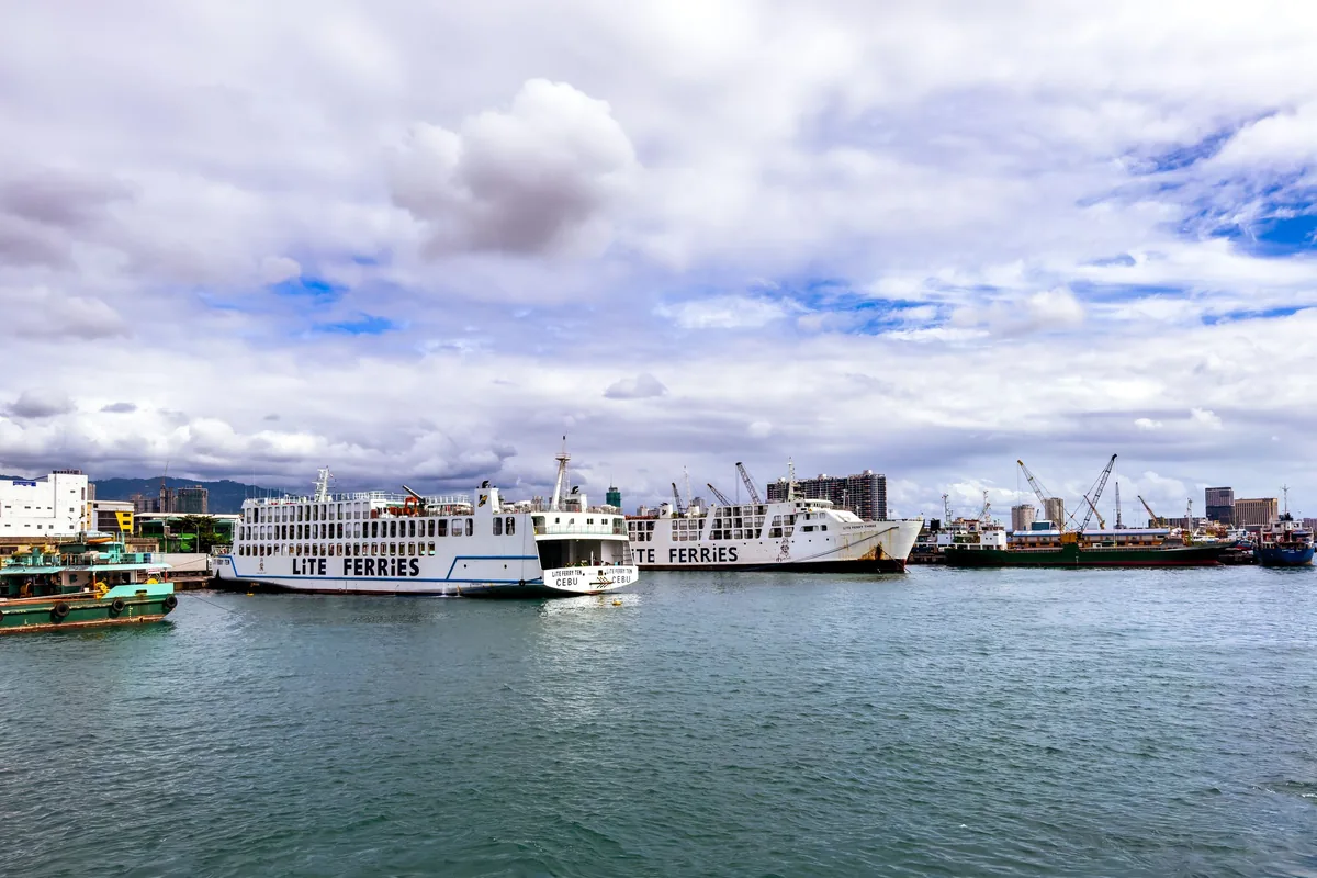 Ferry boats docked at the harbour in Cebu City, Philippines, under a partly cloudy sky